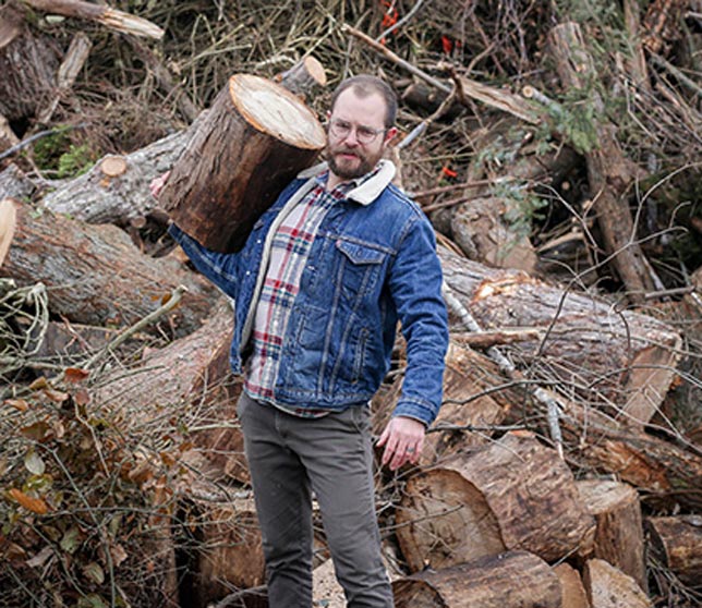 woodrow carrying a large log in front of a brush pile